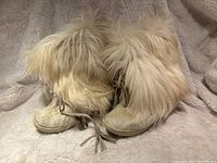 Pair of size 40 fur boots with long tan/beige fur covering and tassel laces visible in front.