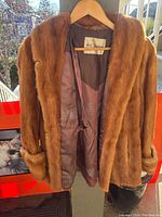 Front view of the medium brown fur coat with open front showing satin lining and internal label.