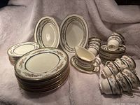 Photo showing cups, saucers, lunch plates, dinner plates, vegetable bowls, and gravy boat arranged on soft fabric