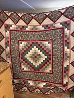 Full view of the quilt showing the overall diamond and floral patchwork pattern with multiple borders.