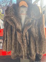 Front view of raccoon fur coat on hanger outdoors