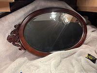Full view of the oval mirror showing the entire frame and wood carving detail.