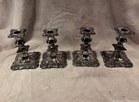Four antique Victorian Sheffield plated candlesticks shown from front
