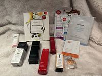 Photo shows the collection of unopened skincare and beauty items including serums, face masks, a small perfume bottle, and boxed items.