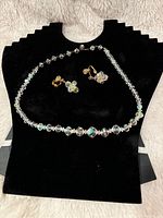 Full view of vintage Borealis crystal necklace and matching clip-on earrings displayed on black jewelry bust.
