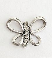 Close-up image showing butterfly pendant with sterling silver loops forming the wings and a row of seven diamonds in the body center.