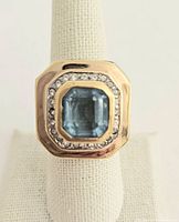 Front view showing large rectangular blue stone surrounded by white rhinestones and marked gold-tone setting