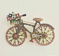 Front view of the rhinestone bicycle brooch showing colorful rhinestones and flower basket detail on the handlebars.