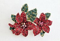 Close-up of red poinsettia flower brooch with detailed rhinestone decoration.