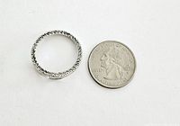 Photo showing round silver pendant with diamonds next to a quarter for size reference.