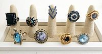 All nine vintage/antique cocktail rings displayed on beige ring holders, various blue stones and metalwork