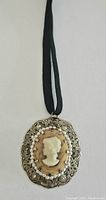Full view of vintage cameo pendant choker on black ribbon showing pendant and ribbon length.