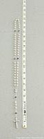 Full view of the vintage pearl and black stone rosary with measuring tape showing length around 20 inches.
