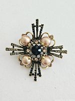 Front view of vintage rhinestone and faux pearl brooch on white background showing full design and condition.