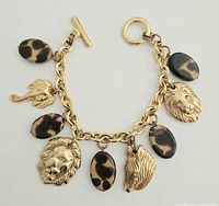 Photo showing entire gold-tone link charm bracelet with safari animal heads and leopard print oval beads, toggle clasp visible.