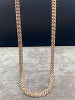 Necklace laid flat showing full length and mesh chain pattern with rose gold finish