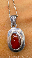 Close-up of the amber pendant on a chain, showing the silver setting and amber color and texture.