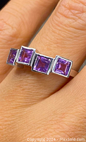 Close-up photo of the sterling silver ring with four square purple amethysts set in a row on finger, showing side angle and stone setting details.