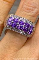 Close-up view of the sterling silver ring on finger showing vibrant purple iolite stones and clear stones along edges.