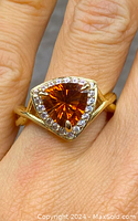 Close-up photo of ring on finger showing triangular citrine gemstone and clear stones.