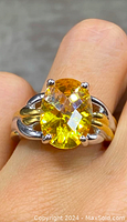 Close-up photo focusing on the oval yellow faceted stone and the sterling silver with gold gilt band detail.