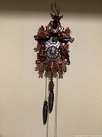 Full view of hand-carved cuckoo clock with weights and pendulum hanging