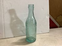 Clear image of standing vintage Coca Cola bottle showing overall shape and bluish tint.