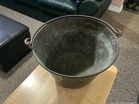 Top and inner view of vintage copper pail showing patina and wear inside and on rim.