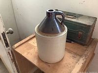 Full view of vintage stoneware jug showing overall condition and form placed on wooden surface.