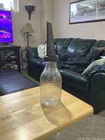 Photo showing full vintage oil bottle with metal spout on table in living room setting.