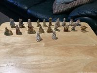 Twenty-one Wade Red Rose Tea nursery rhyme ceramic figurines arranged on a wooden surface, showing the entire lot from a distance.