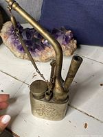 Side view of an antique Chinese metal opium pipe showing engraved Chinese character and hinged lid