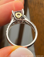 Close-up image of engagement ring showing the rectangular clear central stone, sterling silver band with gold accent beneath the stone, and clear stones set into the split shank band.