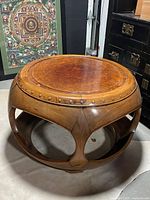 Full view of round drum table showing burl top, decorative studs and openwork base