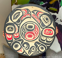 Front view of round plaque held by person to show scale and design