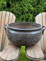 Front view of round bronze burner showing full dragon relief pattern, two handles and three small legs