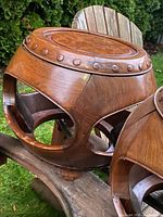 Close-up of one drum stool showing burl veneer seat top, carved stud rim and openwork sides