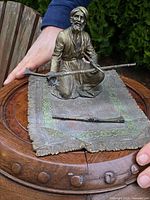 Overall view of bronze sculpture and loose rifle on decorative mat base
