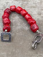 Close-up photo of chunky genuine red coral beads and hammered sterling silver toggle clasp on the bracelet.