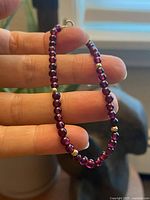 Close-up view of garnet beads with 10k gold beads spaced evenly, showing the bracelet held by fingers with natural light.