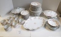 Full set laid out showing the variety and quantity of the 54 pieces in the Bridal Rose pattern including plates, bowls, cups, saucers and two covered casseroles.