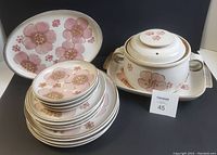 Photo of stack of plates, oval platter, and lidded casserole on black background