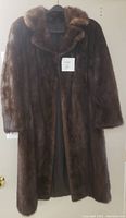 Front view of brown vintage mink fur coat on hanger, showing texture, length, collar, and partial lining view.