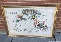 Photo of large framed embroidered textile featuring birds in a tree with sun and inscription, showcasing full artwork and frame.