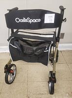 Front view showing black backrest with Oasis Space branding and zippered black mesh carrier under seat.