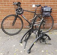 Full view of bicycle leaning against brick wall with Saris car carrier placed in front