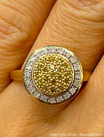 Close-up of ring face showing domed pavé cluster of yellow diamonds surrounded by clear diamond halo.
