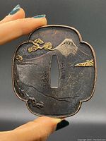 Obverse side showing Mt. Fuji, pine branches, and signature in relief with gold and silver highlights