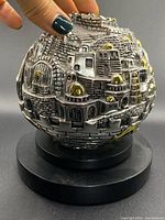 Front angled view of sterling silver village globe showing detailed architecture, gold domes, and black base.