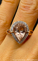 Front view of ring on finger showing pear-shaped morganite and diamond halo